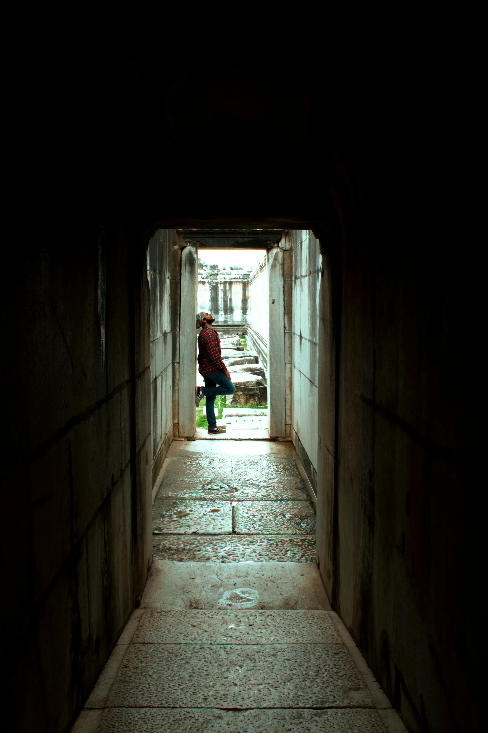 a woman walking out of a tunnel on a brick walkway