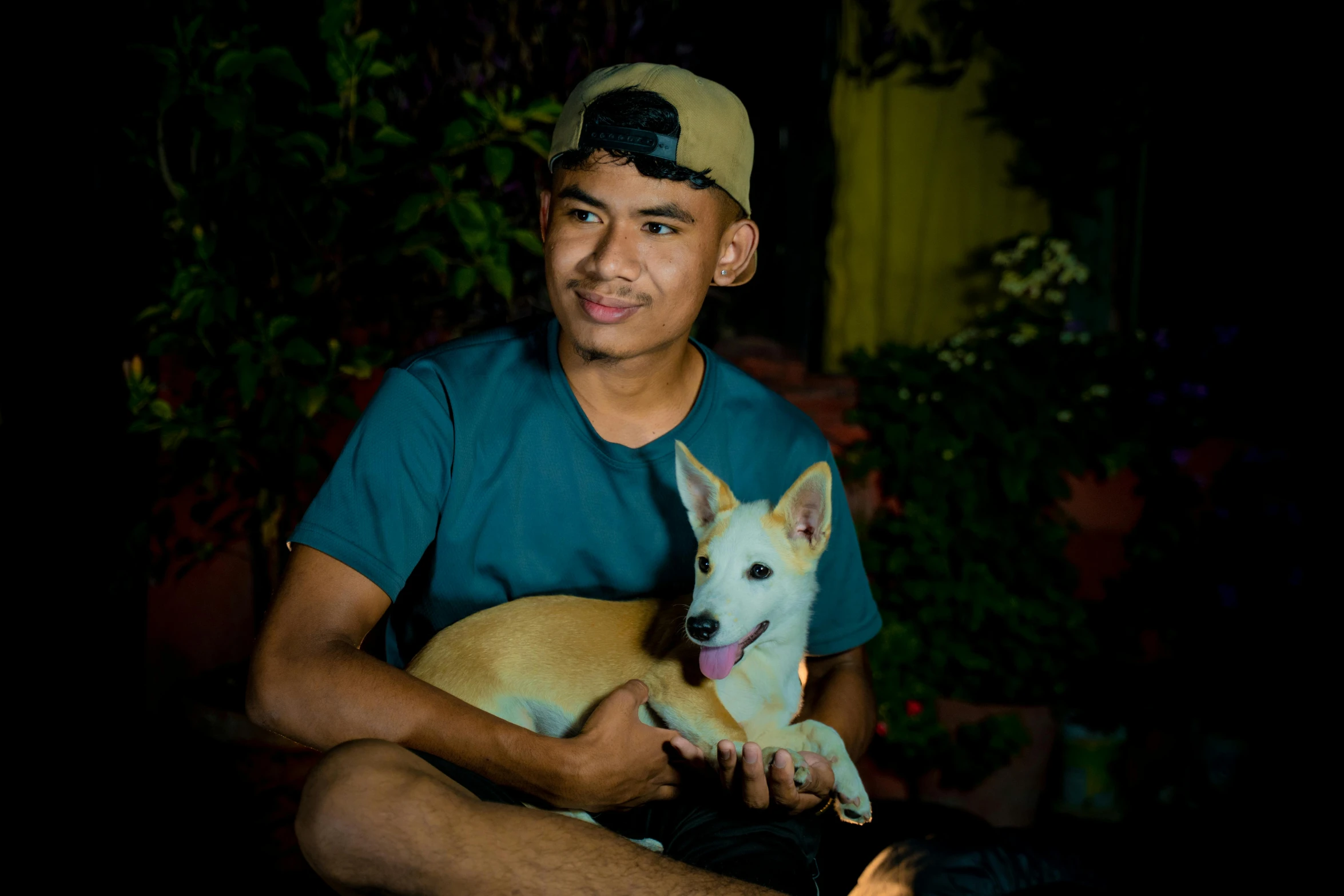 a man sitting on the ground holding a white dog