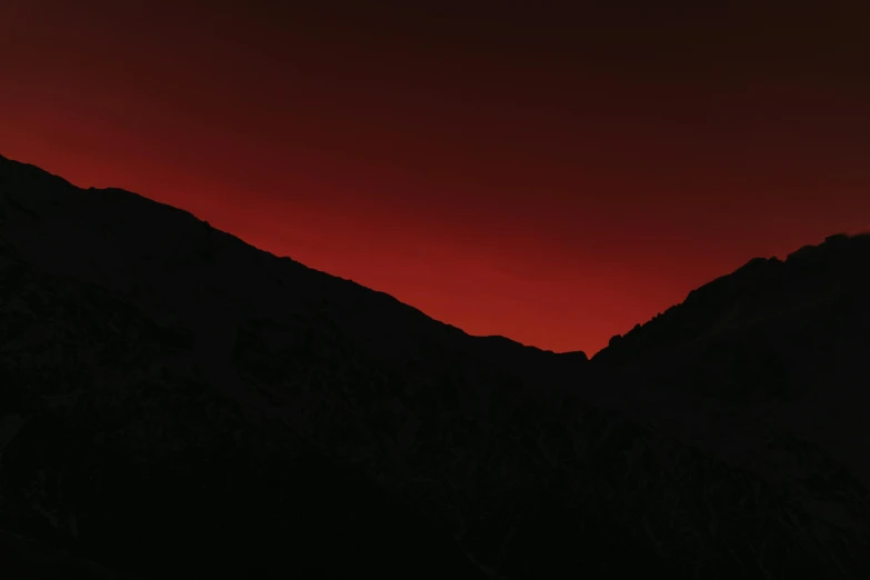 the mountains are silhouetted against an orange sky