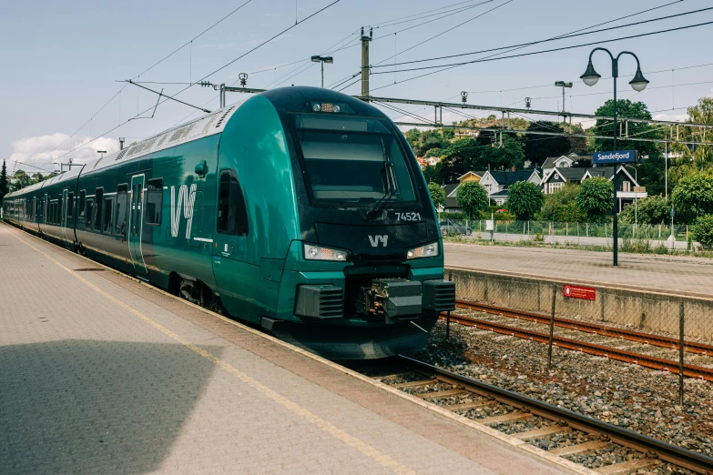 a green train sits at a train station next to an empty platform