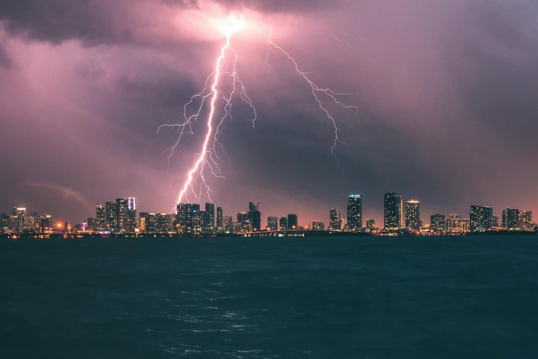 a large city at night with lightning hitting over the top