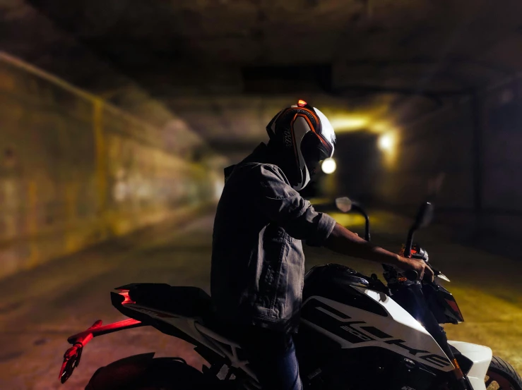 the man is wearing a helmet, riding his motorcycle through the tunnel