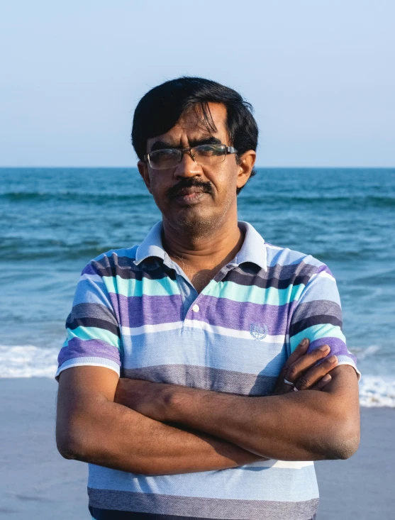 a man in glasses standing on the beach