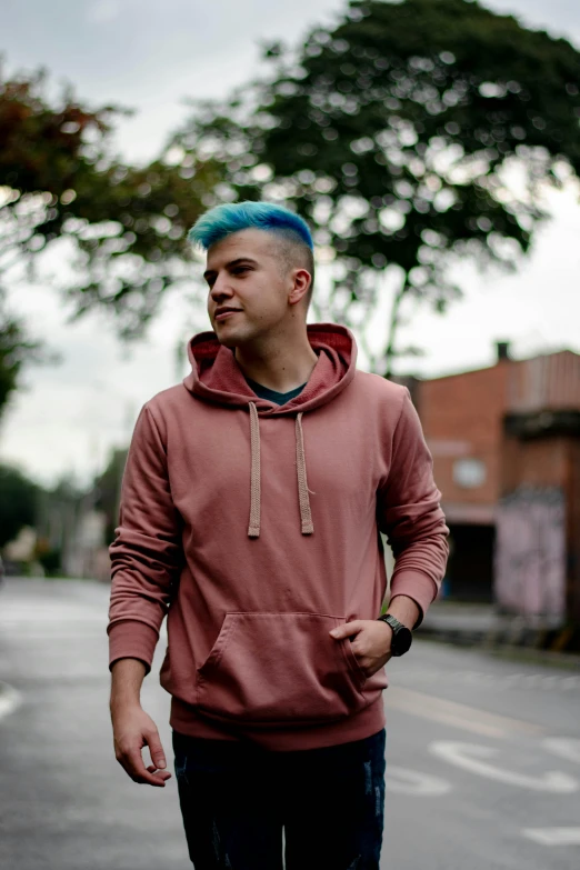 a young man with blue hair and a pink hoodie on