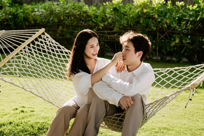 a man and woman sitting in a hammock smiling