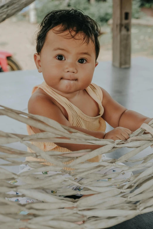 a baby is posing on a hammock under the canopy