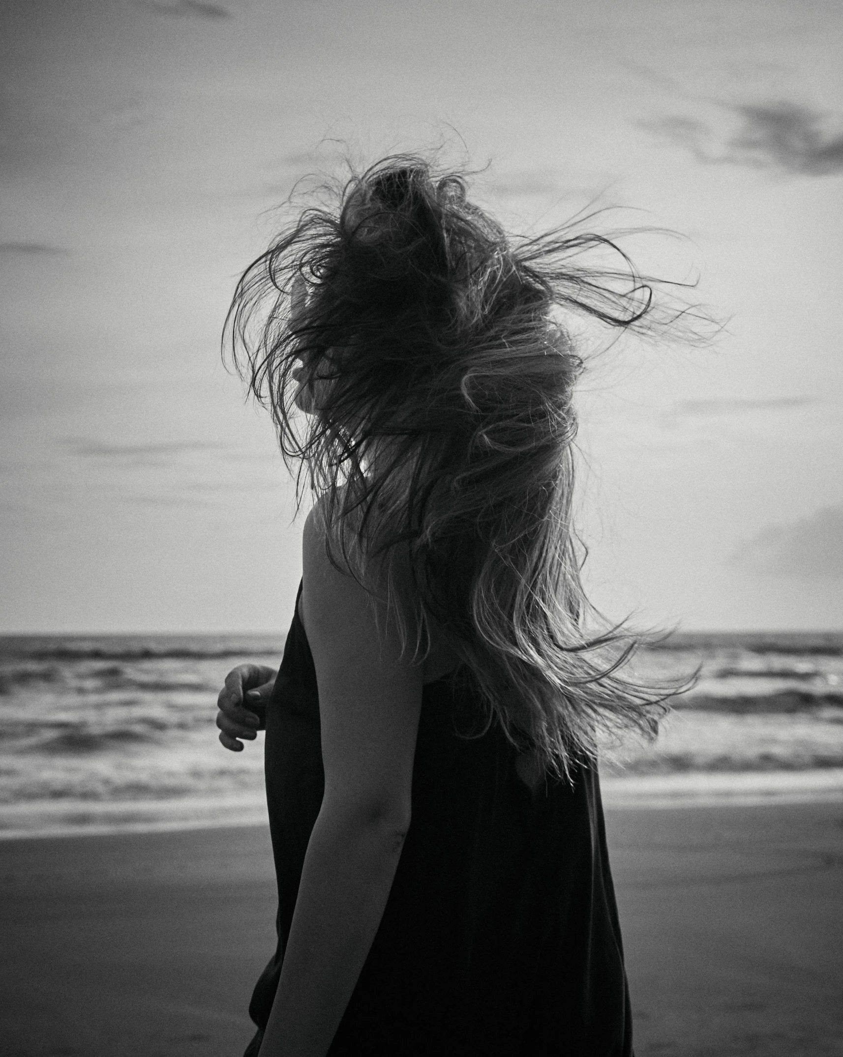 black and white pograph of woman's back at beach