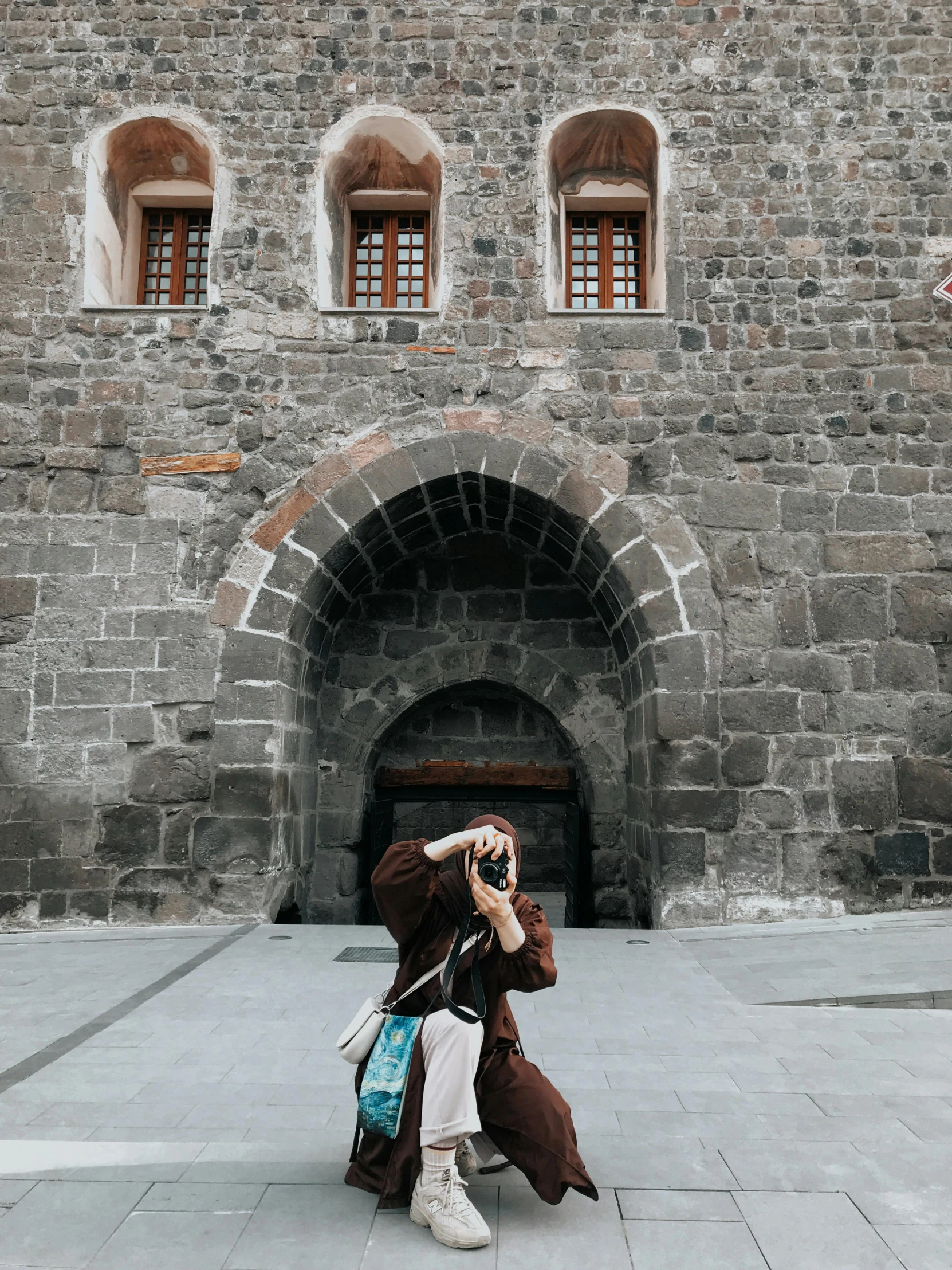 a woman taking a po in front of an old brick building