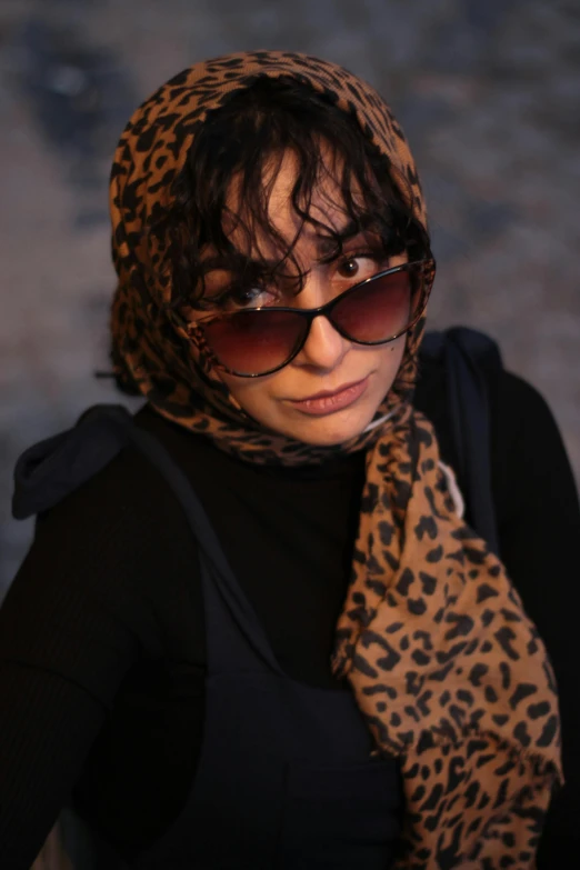 a woman wearing leopard print scarf and sunglasses