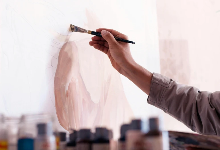 a person is holding a brush and some paint on paper
