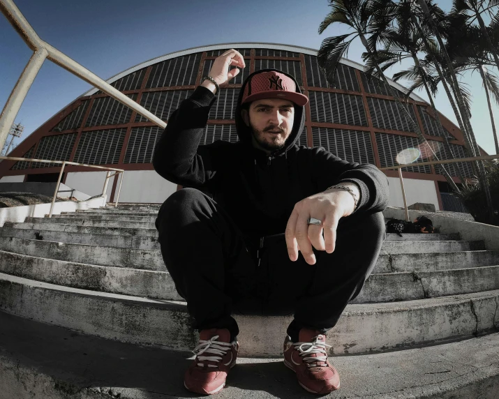 the young man is posing on the steps with his hands behind him