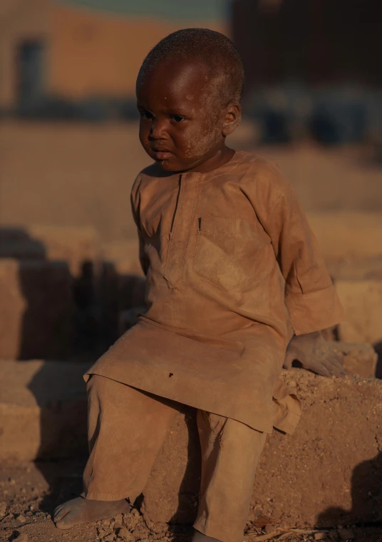 small doll sitting on a rock in sand