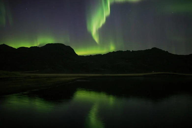 the green and purple northern lights are reflected in the water