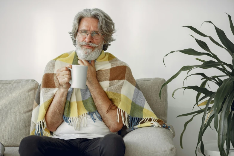 a man in white shirt and plaid scarf drinking from a mug