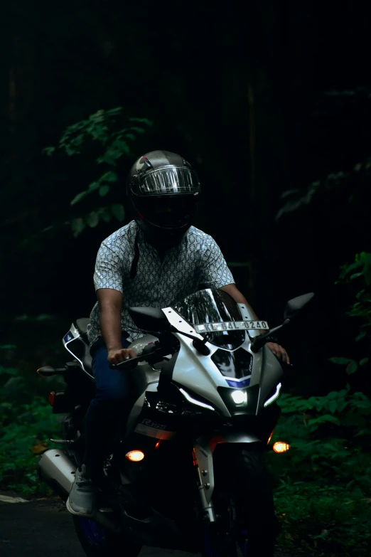 man with helmet on parked motorcycle in forest