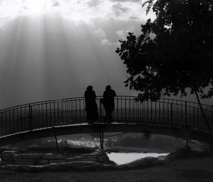 two people standing on the edge of a bridge