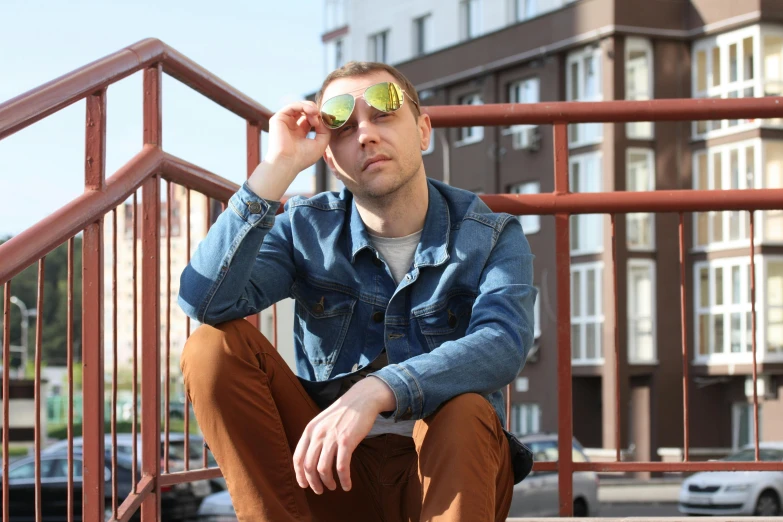 a man in blue denim jacket and yellow tinted glasses