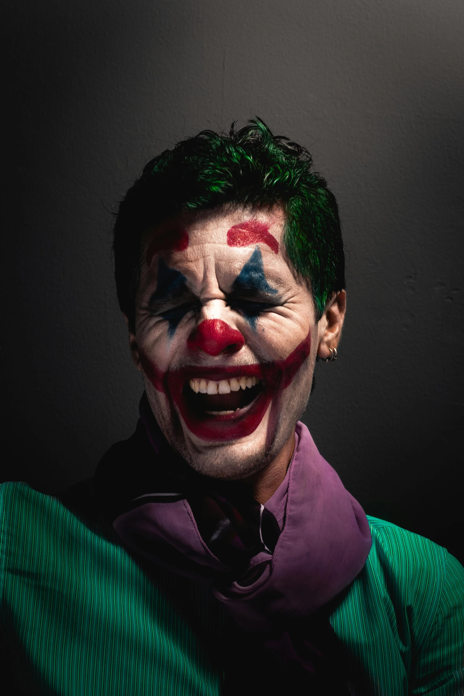 a man with clown makeup and green hair smiles at the camera
