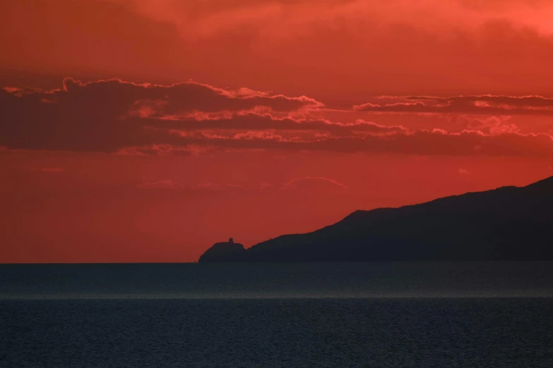 a large red and yellow cloud sitting above water