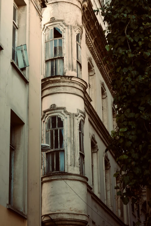 an old looking building with some green trees in the foreground