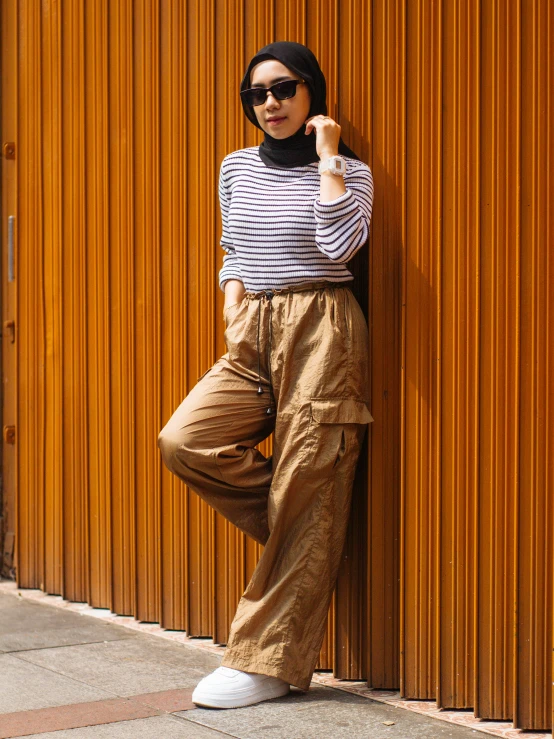 a woman wearing sunglasses leaning against a wall