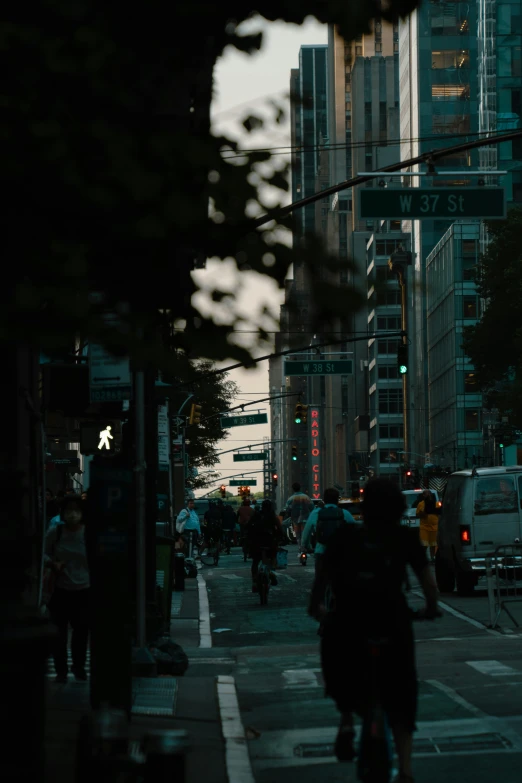 many people with bicycles are walking down the sidewalk