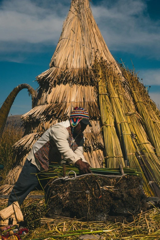 a man working on a large straw roof