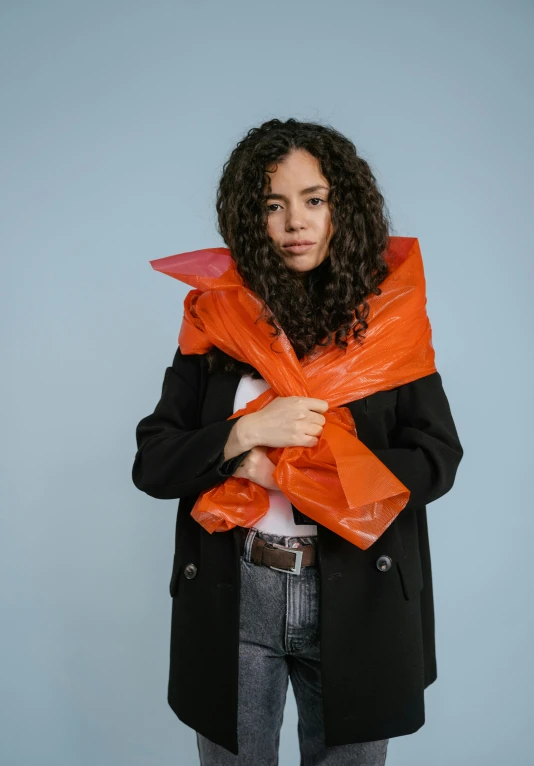 woman in black coat standing with an orange scarf