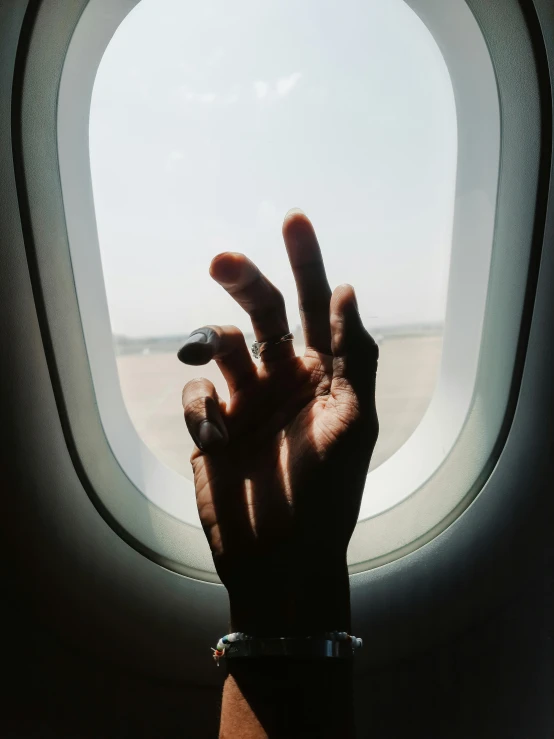 a hand is seen above an airplane window