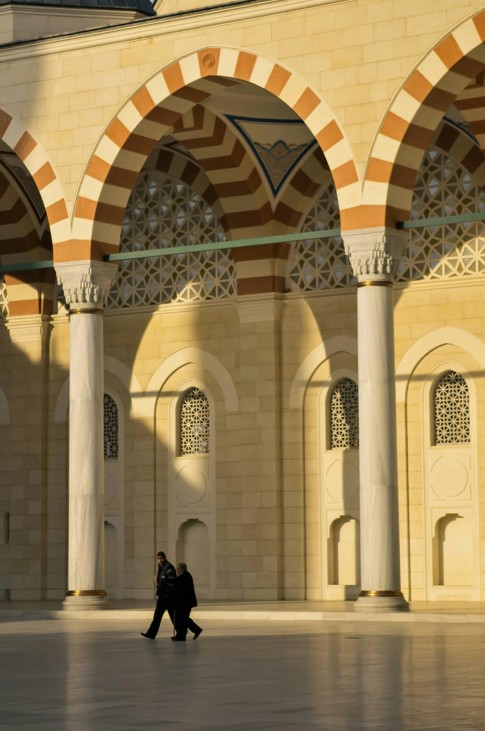 a man walks near an archway and some pillars