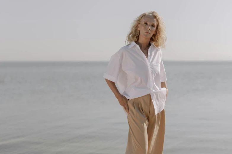 a woman is leaning against the edge of a railing with her hands on her hips