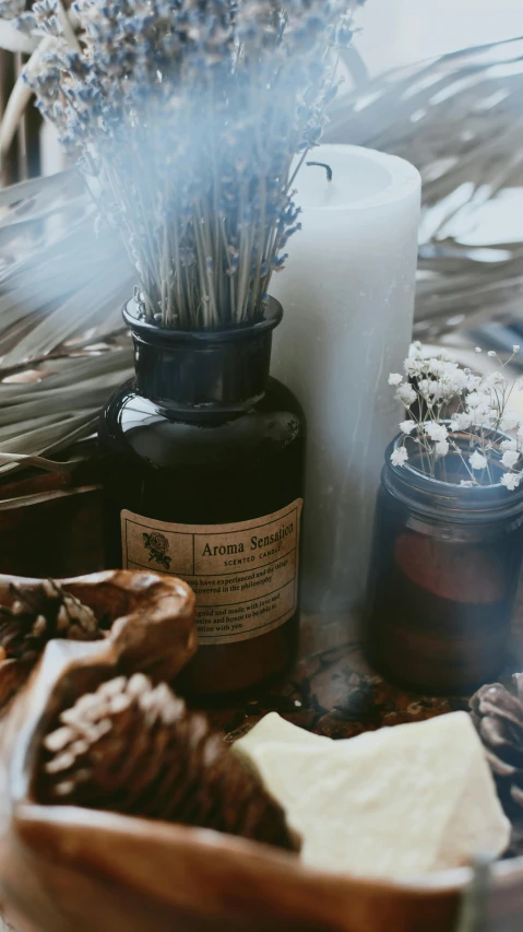 two candles next to a bottle filled with lavender flowers