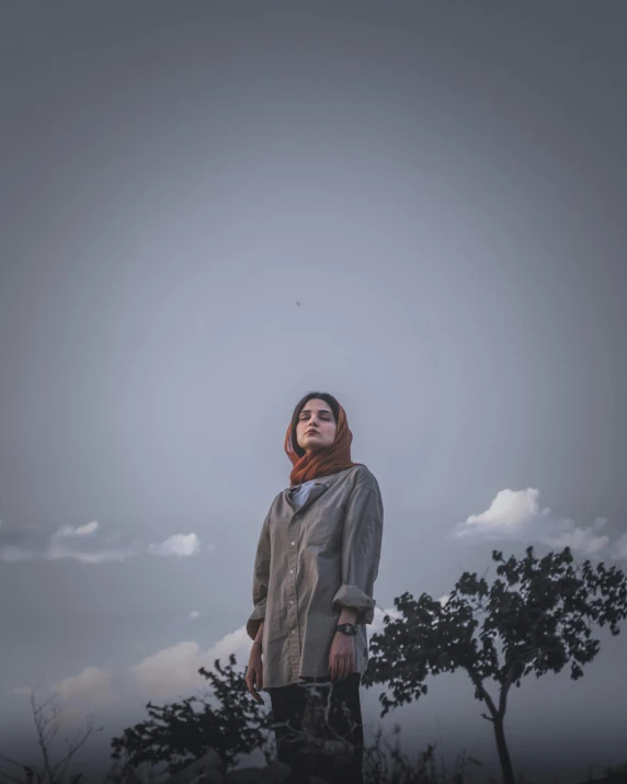 a woman standing on top of a grass covered hillside