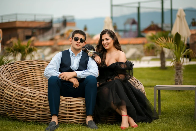 a couple of people sitting on a wicker chair outside