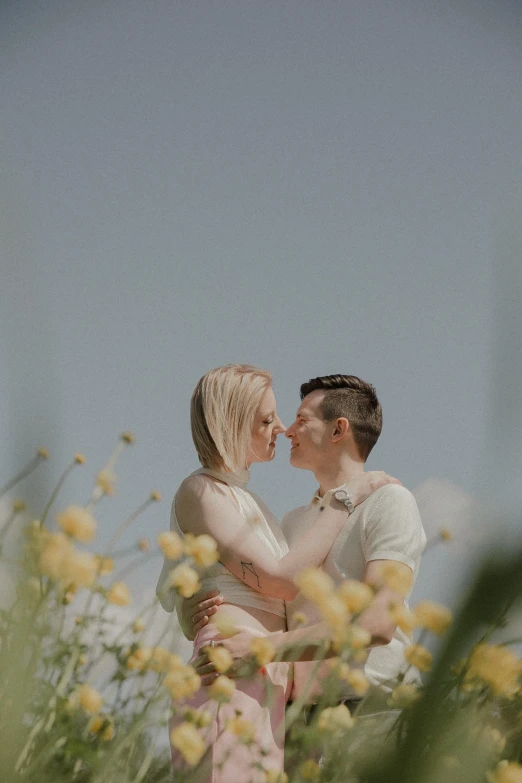 an engaged couple kissing in a field of flowers