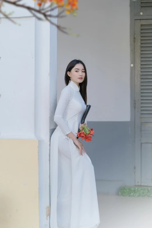 the young asian woman is holding her bouquet in her hand