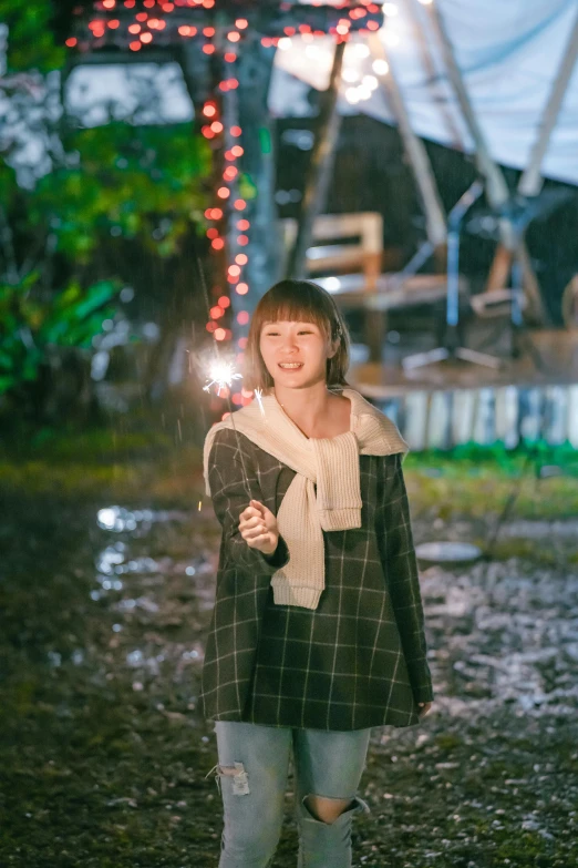 woman standing in park holding sparkler near tent at nighttime