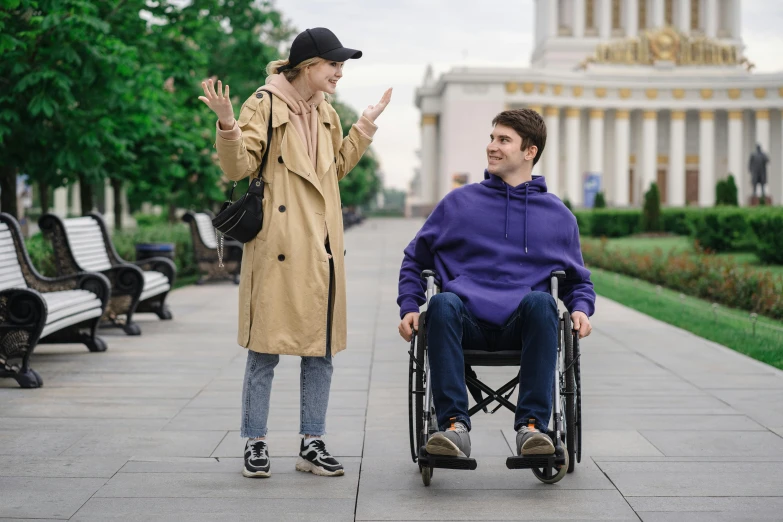 a man in a wheelchair and a woman talking in the background