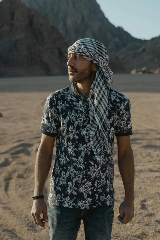 a man in a black and white shirt stands in the desert