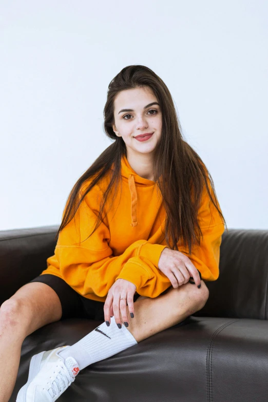 young woman wearing a yellow shirt sitting on top of a couch