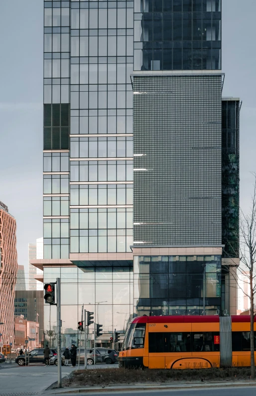 an orange and red bus parked next to some tall buildings