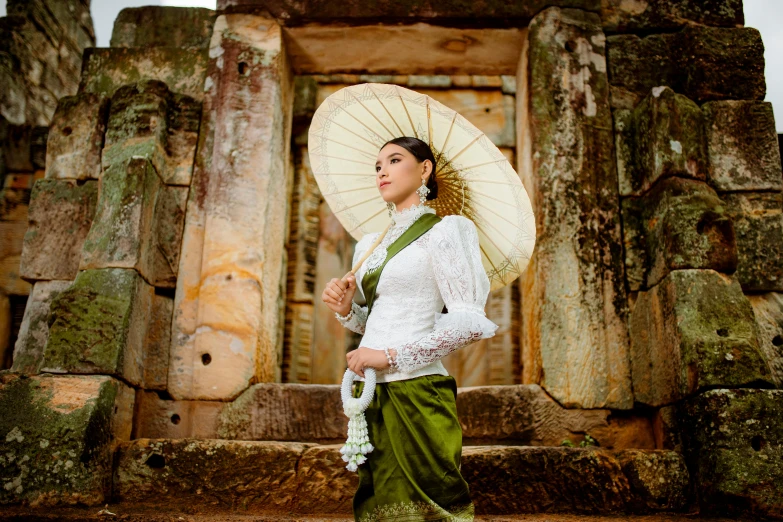 a woman with an umbrella stands in front of ancient architecture