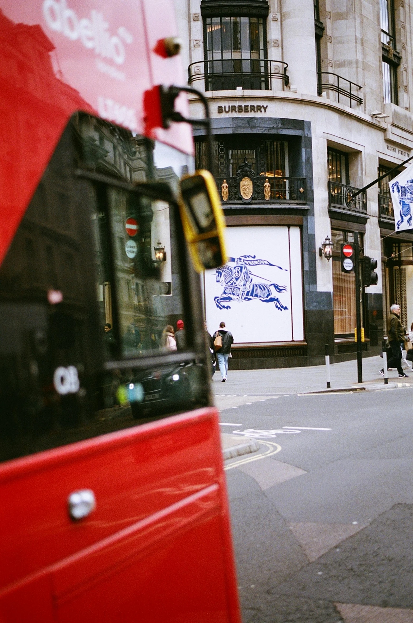 a red double decker bus turning the corner near pedestrians and traffic