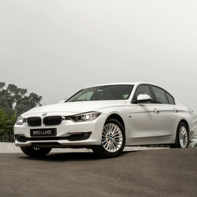 the white bmw is parked on the side of a road