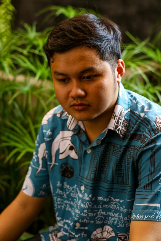 a man sitting down wearing a blue shirt