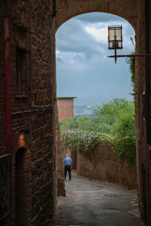 an arched doorway with a man walking down the path in it