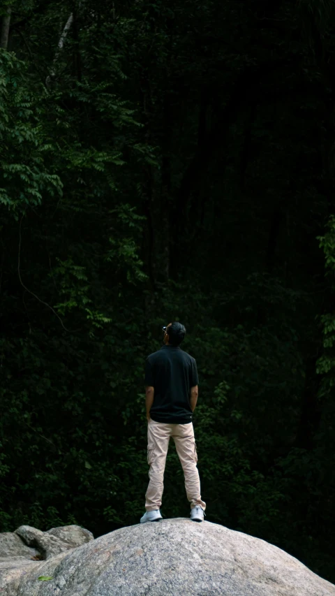 a man is standing on a large rock outside