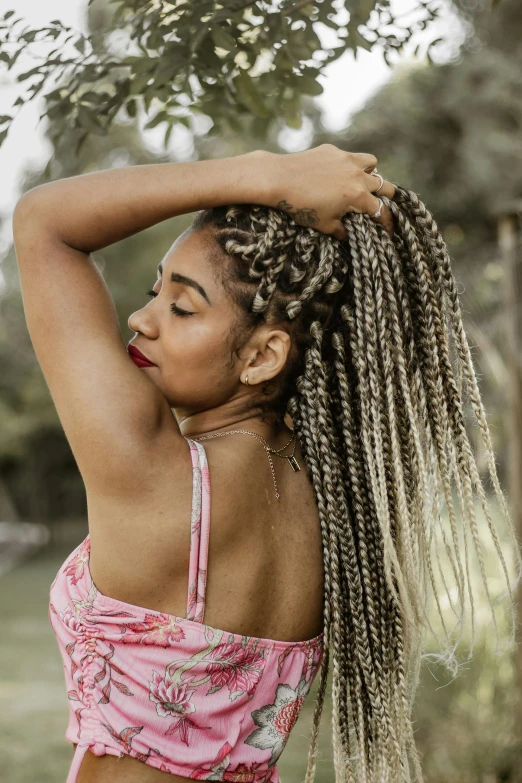 woman with long cornrows and pink bikini top and green grass in the background