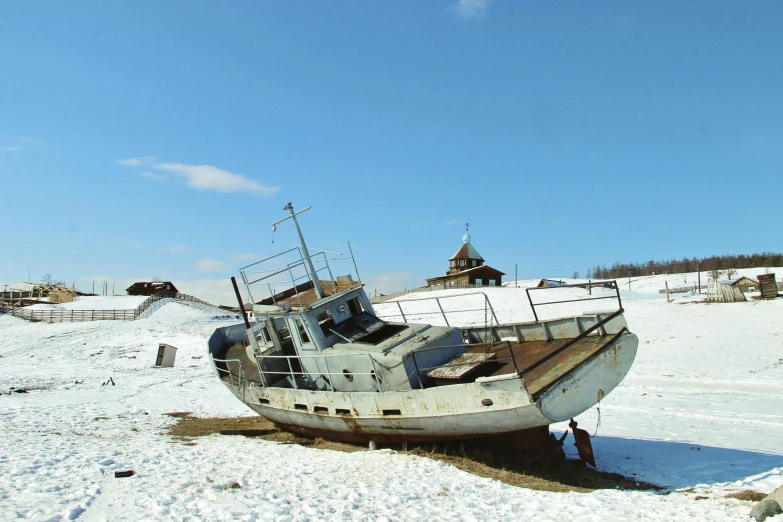 an abandoned boat on the sand in a snowy field