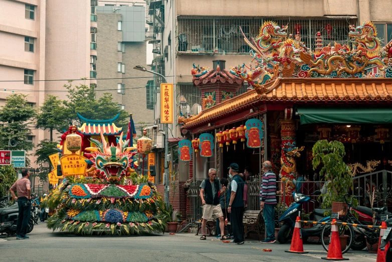 people walk by an elaborate display with flowers on the street